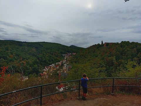 Kind steht klein an einem Geländer über dem Tal, darunter die Häuser im Isenachtal, rechts auf dem Hügel die Klosterruine