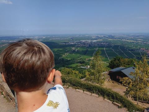 Kind schaut von der Rietburg über Weinberge und Ortschaften in die Rheinebene
