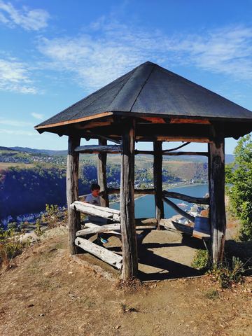 Hölzerne Schutzhütte mit Spitzdach und krummen Stützen auf einer Kuppe über dem Rheintal