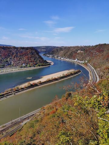 Blick von oben auf den Rhein mit einer langen freigefallenen Sandbank in der Flussmitte, am Ufer Bahngleise